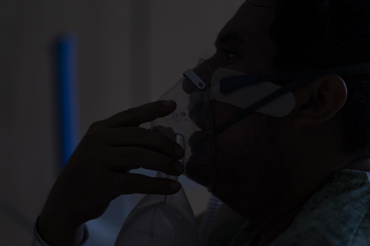 Julio Valladares, a 46-year-old COVID-19 patient, struggles with breathing while talking to a nurse at Providence Holy Cross Medical Center in Los Angeles, Tuesday, Dec. 14, 2021. At the medical center, just 17 coronavirus patients were being treated there Friday, a small fraction of the hospital's worst stretch. Nurse manager Edgar Ramirez said his co-workers are weary but better prepared if a wave hits. (AP Photo/Jae C. Hong)