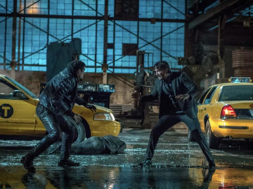 Keanu Reeves as John Wick fighting a gangster in the taxi warehouse.