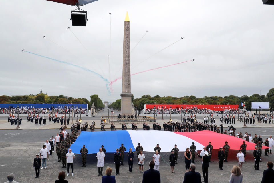 Members of medical staff pose with the French flag as they take part in the annual Bastille Day military ceremony on the Place de la Concorde in Paris, Tuesday, July 14, 2020. France are honoring nurses, ambulance drivers, supermarket cashiers and others on its biggest national holiday Tuesday. Bastille Day's usual grandiose military parade in Paris is being redesigned this year to celebrate heroes of the coronavirus pandemic. (Ludovic Marin, Pool via AP)