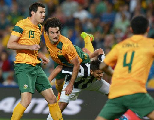 Mile Jedinak (C), de Australia, salta sobre un defensa de Costa Rica para conectar un golpe de cabeza, en partido amistoso jugado el 19 de noviembre de 2013 en Sídney (AFP | Greg Wood)