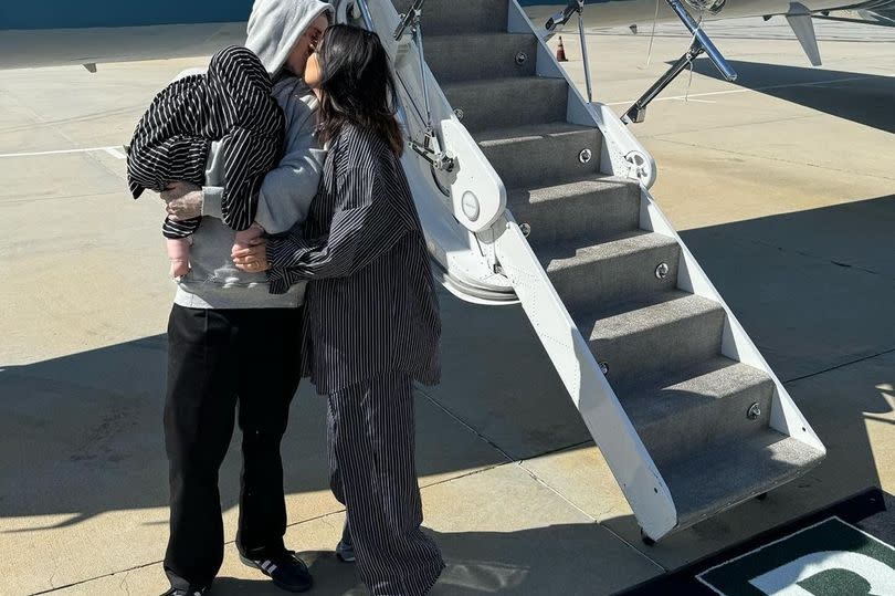 Kourtney Kardashian in front of a private jet with Travis Barker and their baby son Rocky