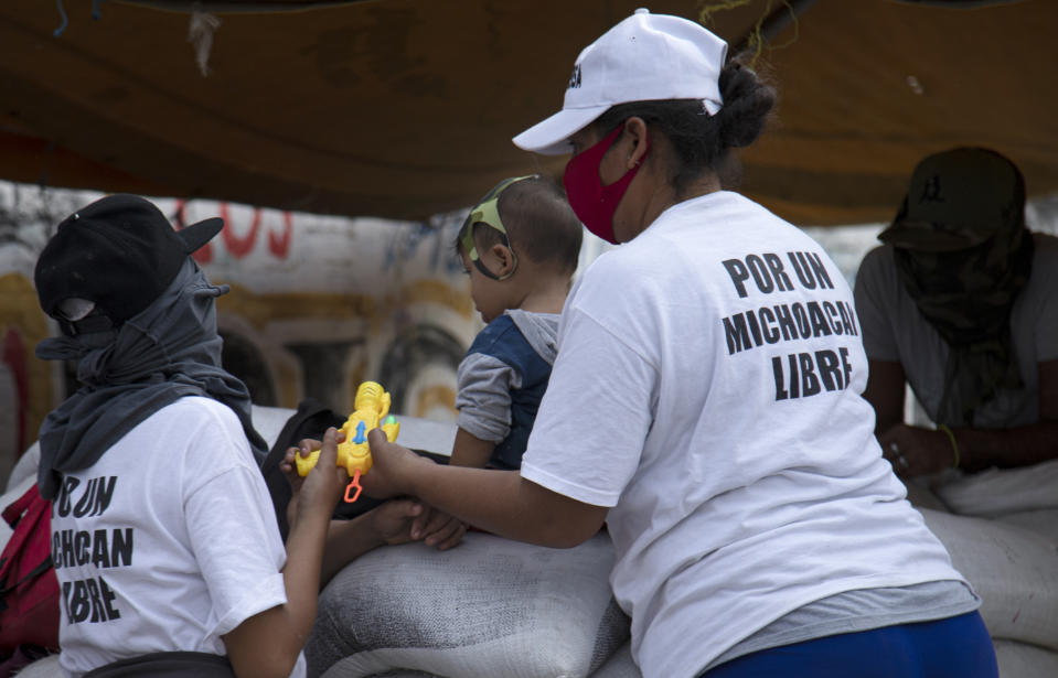 Women who say they are part of a female-led, self-defense group wear T-shirts with a message that reads in Spanish: "For a free Michoacan," as a toddler sits on a sandbag that is part of their check-point to protect the entrance of their town El Terrero, in Michoacan state, Mexico, Wednesday, Jan. 13, 2021. In the birthplace of Mexico’s vigilante “self-defense” movement, the new group has emerged entirely made up of women, who carry assault rifles and post roadblocks to fend off what they say is a bloody incursion into the state of Michoacán by the violent Jalisco cartel. (AP Photo/Armando Solis)