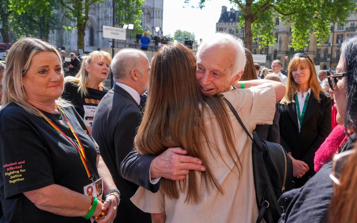 Chairman of the infected blood inquiry Sir Brian Langstaff with victims and campaigners outside Central Hall in Westminster