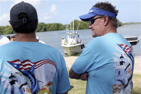 U.S. artist and conservationist Guy Harvey, (R), leads a group of volunteers along the San Juan estuary system for the second "mega cleanup" of garbage from the waterway, in San Juan October 26, 2013. REUTERS/Alvin Baez