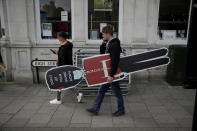 A worker carries a cutout of a guardsman, with a warning to remind people not to let their guard down with regards to coronavirus, as he looks for a suitable place to put it up, to coincide with non-essential shops being reopened this week, opposite Windsor Castle, in Windsor, England, Wednesday, April 14, 2021. Britain's Prince Philip, husband of Queen Elizabeth II, died Friday April 9 aged 99. His funeral service will take place on Saturday at Windsor Castle. (AP Photo/Matt Dunham)