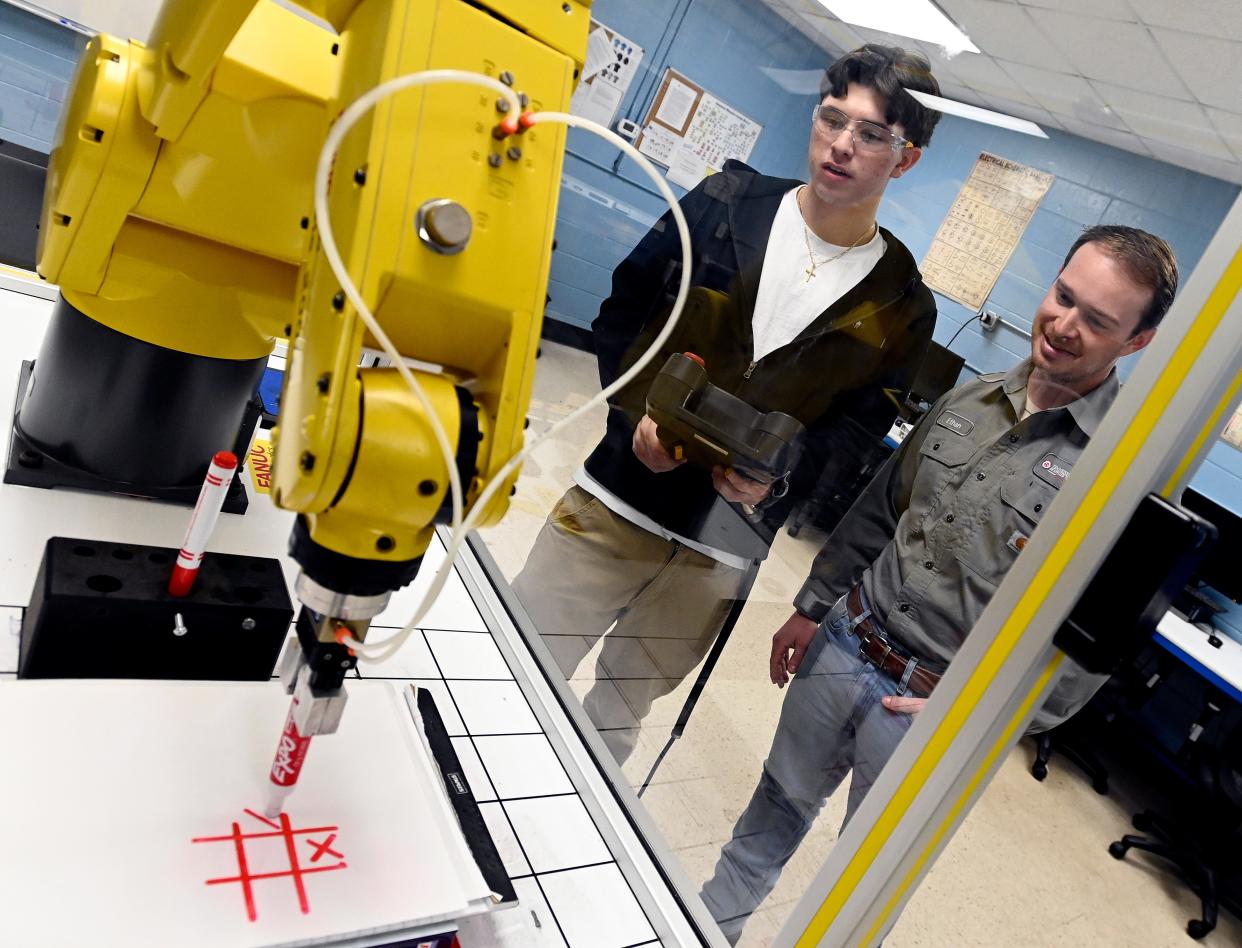 Industrial Maintenance Instructor Ethan Copas, right, watches Aunder Sherrick, 18, control a Fanuc training robot during a class at the Tennessee College of Applied Technology on Thursday, March, 28, 2024, in Portland, Tenn. Students are taking classes to improve their skills for jobs with in-demand industries. There are two job openings for every available skilled worker in Tennessee.