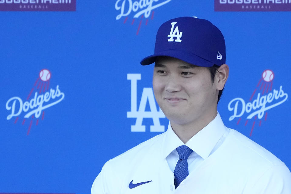 Los Angeles Dodgers' Shohei Ohtani smiles while wearing a jersey and baseball cap during a news conference at Dodger Stadium Thursday, Dec. 14, 2023, in Los Angeles. (AP Photo/Marcio Jose Sanchez)