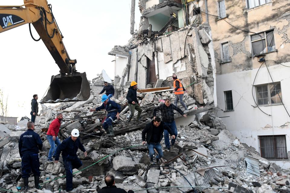 TOPSHOT - Emergency workers clear debris at a damaged building in Thumane, 34 kilometres (about 20 miles) northwest of capital Tirana, after an earthquake hit Albania, on November 26, 2019. - Four people died and some 150 were slightly injured in Albania after a 6.4 magnitude earthquake, the strongest in decades, rocked the Balkan country early Tuesday. The epicentre of the quake was about 34 kilometres (about 20 miles) northwest of Tirana, according to the European-Mediterranean Seismological Centre. (Photo by Gent SHKULLAKU / AFP) (Photo by GENT SHKULLAKU/AFP via Getty Images)