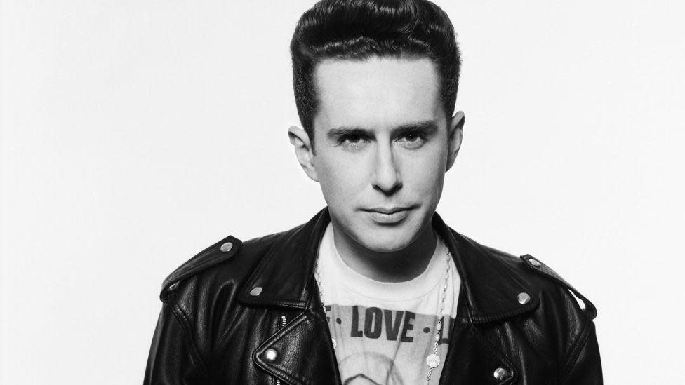 Black and white image of singer Holly Johnson, who has short dark hair and is wearing a black leather jacket and a t-shirt with an image of the Virgin Mary and the word Love on it