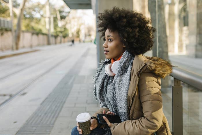 A woman sits alone waiting for a bus