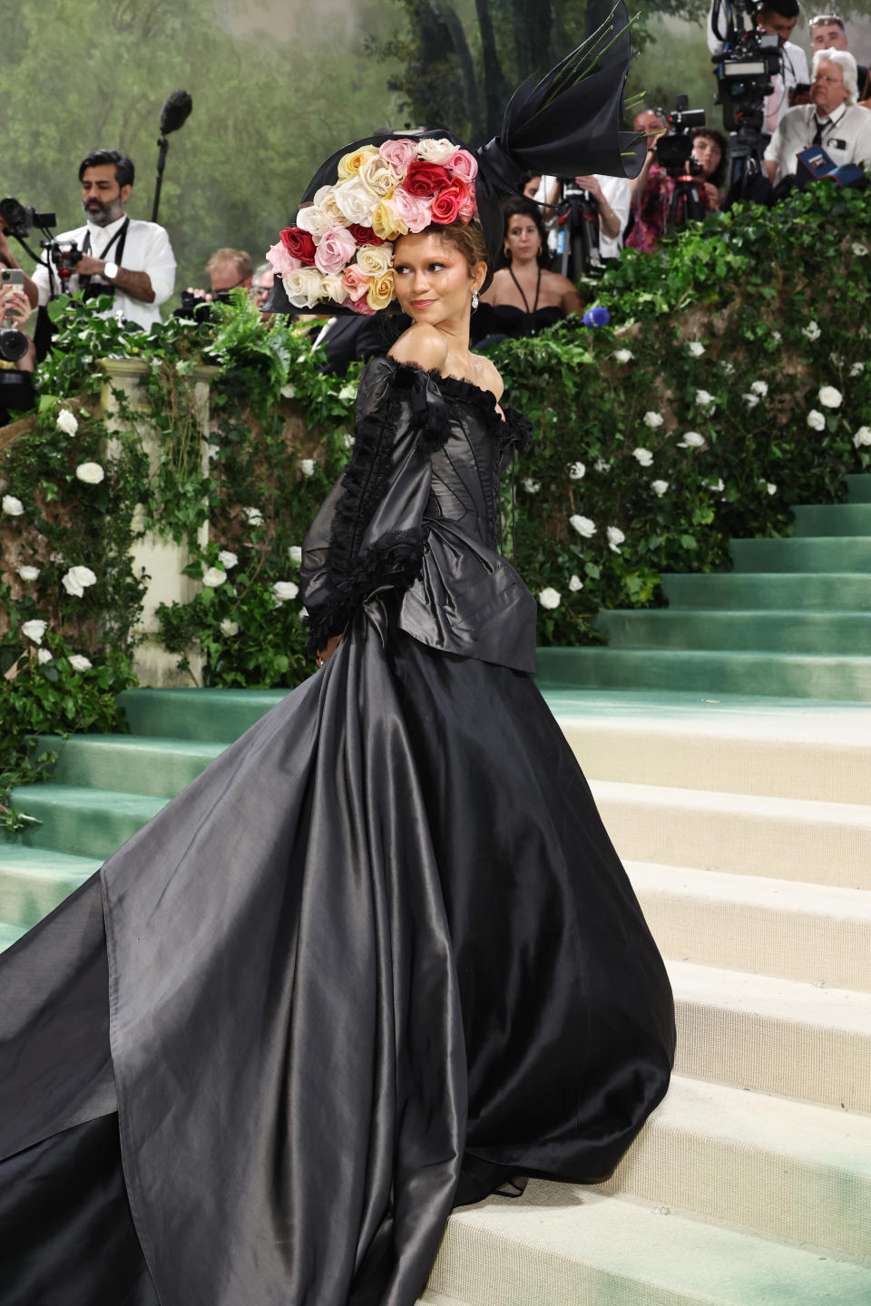 Zendaya with a flower hat on the Met Gala red carpet stairs.