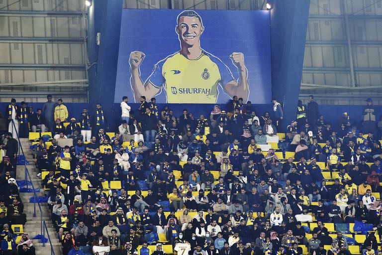 Hinchas de Al-Nassr bajo un cartel con la imagen de Cristiano Ronaldo en su debut oficial
