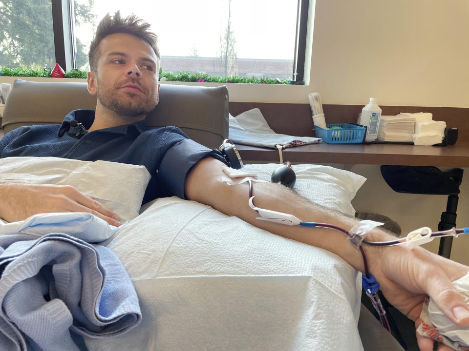 Dylan Smith donates blood platelets at Bloodworks Northwest, where he works as a donor services supervisor, Friday, Dec. 15, 2023, in Vancouver, Wash. More gay and bisexual men can now donate blood in the U.S., and many in Washington state are doing so. (AP Photo/Claire Rush)