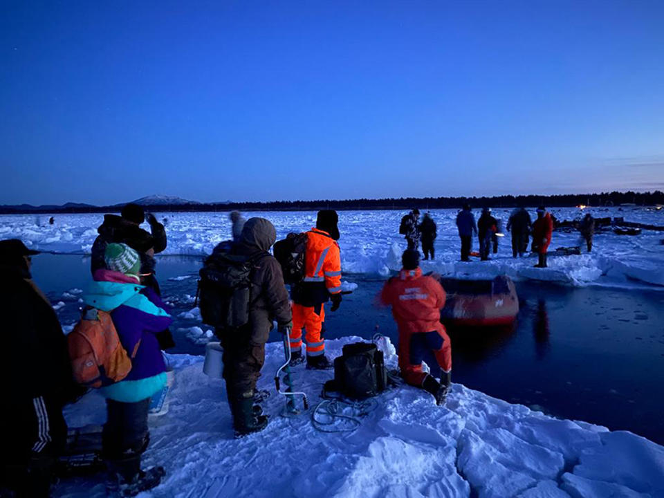 In this Tuesday, Jan. 28, 2020 photo released by the Russia Emergency Situations Ministry press service, showing rescuers in foreground as they help a group of fishermen to get to the land, using a small boat at the Mordvinov's Bay, the island of Sakhalin in eastern Siberia, Russia. Russia's emergency services have rescued 536 ice fishermen after they got stranded on a giant ice floe that broke off the island of Sakhalin in eastern Siberia. (Russia Emergency Situations Ministry press service via AP)