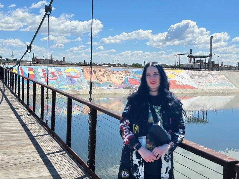 Shannon Palmer, aka Deadhand, stands in front of her previous work on the levee on Monday, May 13, 2024.