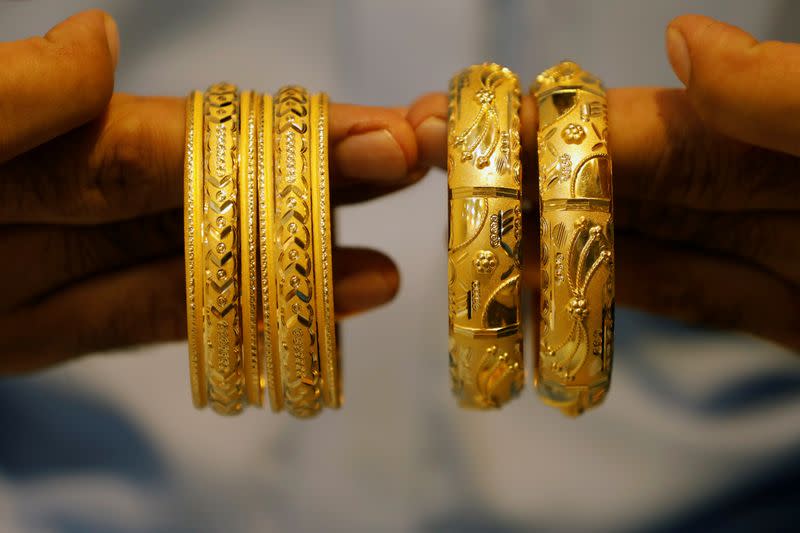 A man checks gold bangles sets at a shop selling bridal jewellery, in Peshawar