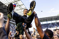 St. Pauli coach Fabian Huerzeler is lifted by fans who invaded the field after their team won 3-1 during a second division, Bundesliga, soccer match between FC St. Pauli and VfL Osnabrueck, at the Millerntor Stadium, in Hamburg, Germany, Sunday, May 12, 2024. St. Pauli has returned to the Bundesliga after a 3-1 win over relegated Osnabrück in Germany’s second division. (Axel Heimken/dpa via AP)