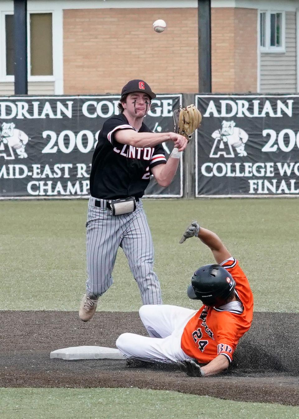 Clinton's Ryan Tschirhart throws to first for a double play after getting a force out at second base while Hudson's Anthony Arredondo slides into the base during Saturday's MHSAA Division 3 regional championship game at Nicolay Field on the campus of Adrian College.