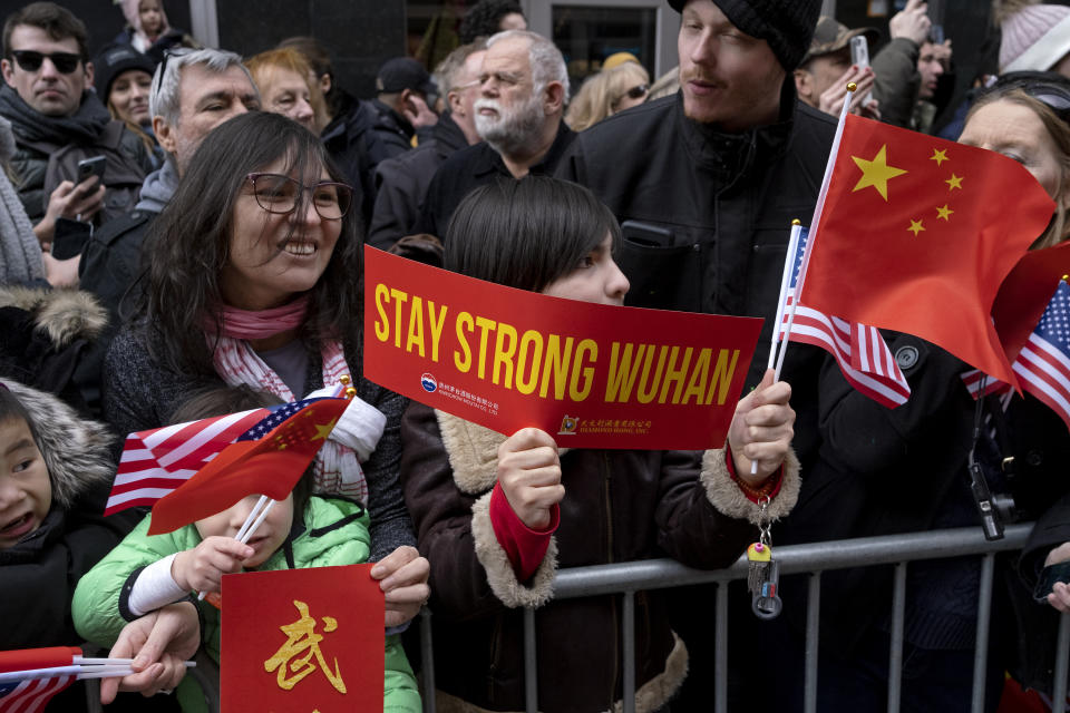 A paradegoer holds a sign of support for Wuhan, China, at the center of the coronavirus outbreak, as participants in the Lunar New Year parade pass by in the Chinatown neighborhood of New York, Sunday, Feb. 9, 2020. (AP Photo/Craig Ruttle)