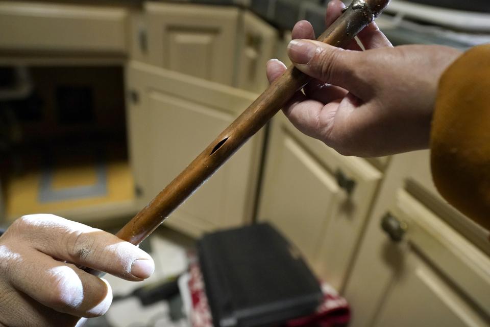 CORRECTS SPELLING OF LAST NAME TO VALERIO, NOT VALERIA - Handyman Roberto Valerio, left, hands homeowner Nora Espinoza the broken pipe after removing it from beneath her kitchen sink on Saturday, Feb. 20, 2021, in Dallas. (AP Photo/Tony Gutierrez)