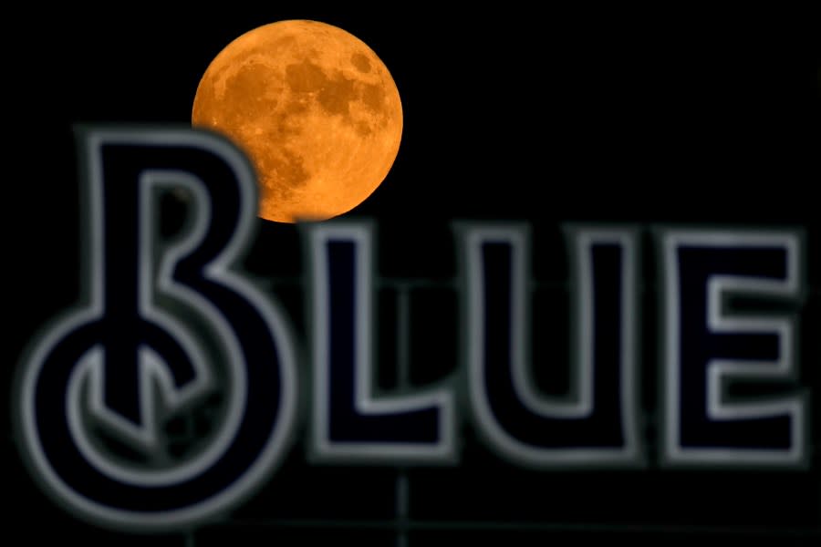 The full moon rises beyond a sign in the outfield during a baseball game between the Kansas City Royals and the Pittsburgh Pirates on Wednesday, Aug. 30, 2023, in Kansas City, Mo. The moon was a rare blue supermoon, named so because it was the second full moon in August, thus the blue label, and it was unusually close to Earth, therefore a supermoon. (AP Photo/Charlie Riedel)