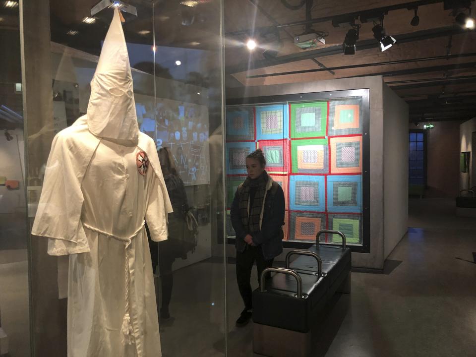 In this Nov. 24, 2019 photo, visitors at the International Slavery Museum in Liverpool, England, examine a display of a 1920s-era Ku Klux Klan outfit from Port Jervis, N.Y. The museum seeks to tell the story of the enslavement of people from Africa and how the British city benefited from human bondage. (AP Photo/Russell Contreras)