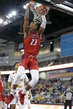 A basketball player dunks.