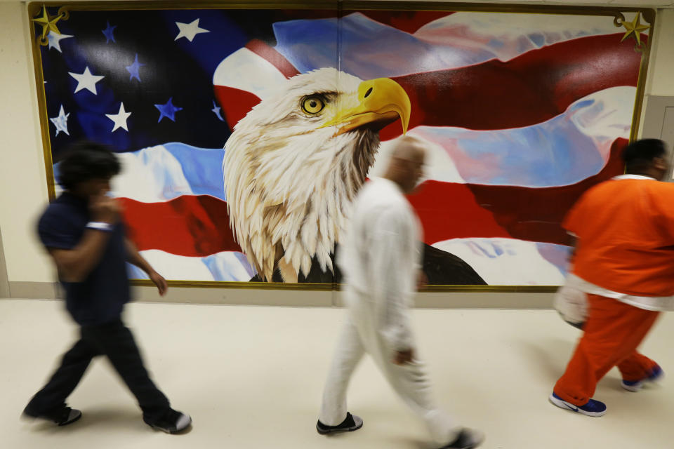 FILE - In June 21, 2017, file photo, detainees walk past a mural in the Northwest Detention Center in Tacoma, Wash., during a media tour of the facility. The Trump administration is opposing Washington state’s effort to make a privately run, for-profit immigration jail pay detainees minimum wage for the work they do. Washington Attorney General Bob Ferguson sued The GEO Group in 2017, saying its Northwest Detention Center in Tacoma must pay the state minimum wage to detainees who perform kitchen, janitorial and other tasks. (AP Photo/Ted S. Warren, File)