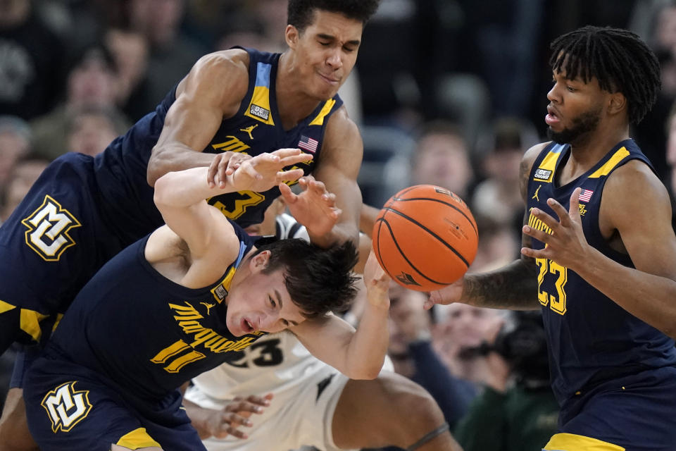 Marquette guard Tyler Kolek (11), forward Oso Ighodaro (13) and forward David Joplin (23) try to gain control the ball during the second half of the team's NCAA college basketball game against Providence, Tuesday, Dec. 19, 2023, in Providence, R.I. (AP Photo/Steven Senne)