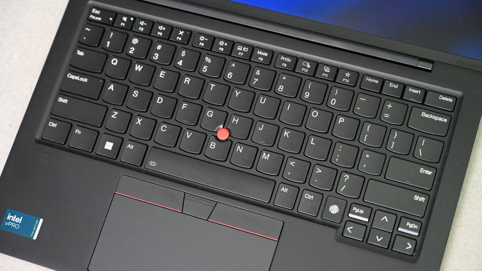 Radharc ón mbarr anuas ar mhéarchlár Lenovo ThinkPad X1 Carbon, le bata dearg dírithe idir íochtair na n-eochracha G agus H.