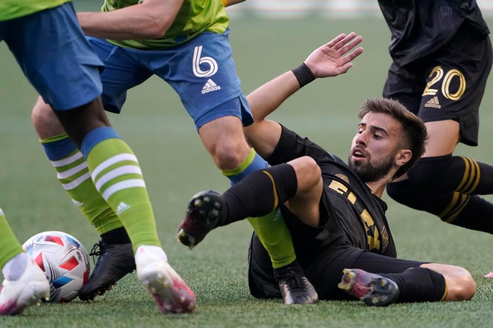L'attaquant du Los Angeles FC Diego Rossi regarde le ballon alors que le milieu de terrain des Sounders de Seattle Joao Paulo (6) le lance après la chute de Rossi lors de la première moitié d'un match de football de la MLS, le dimanche 16 mai 2021, à Seattle.  (AP Photo/Ted S. Warren)