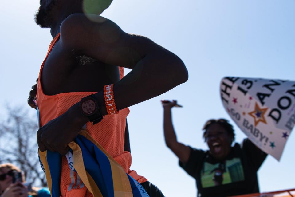 First-place finisher Lawrence Kipkoech crosses the finish line of the 50th Horsetooth Half Marathon while his wife cheers for him on Sunday in Fort Collins.