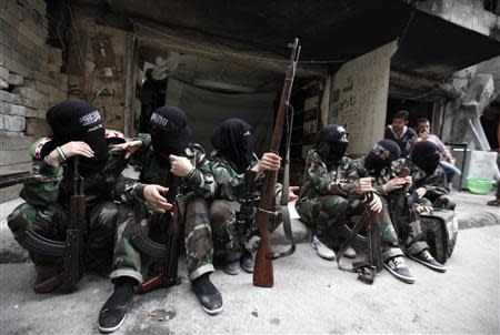 Female members of the "Mother Aisha" battalion sit together along a street in Aleppo's Salaheddine district, September 19, 2013. REUTERS/Loubna Mrie