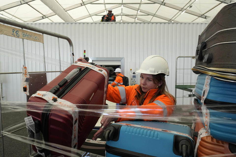 A worker carries a suitcase in the "baggage factory", where athletes' luggages for the Paris 2024 Olympic Games will be collected, are seen in Charles de Gaulle airport, in Roissy-en-France, north of Paris, Tuesday, April 23, 2024 in Paris. (AP Photo/Thibault Camus)