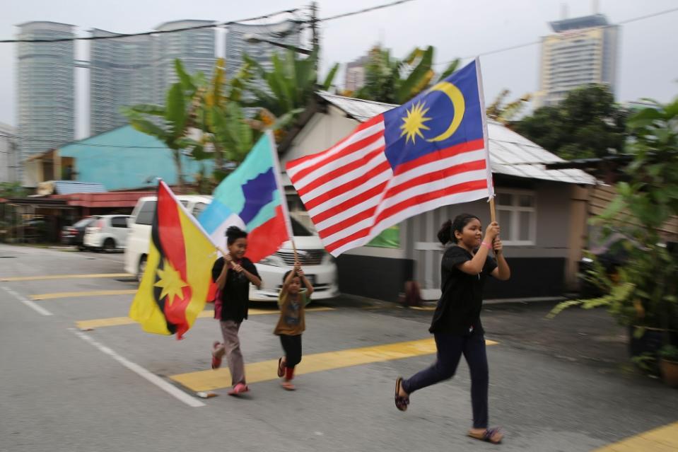 Children are seen running with the Jalur Gemilang as well as the Sarawak and Sabah flags. Sixty years is a long time to be together, but we could get to know each other better, especially those in the Peninsula regarding East Malaysia. — Picture by Yusof Mat Isa