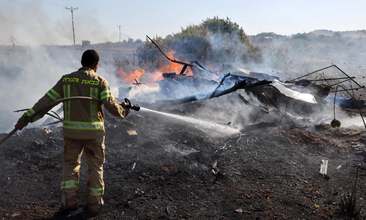 <span>An Israeli firefighter douses flames in a field after rockets launched from southern Lebanon landed on the outskirts of Kiryat Shmona on 4 June.</span><span>Photograph: Jack Guez/AFP/Getty Images</span>