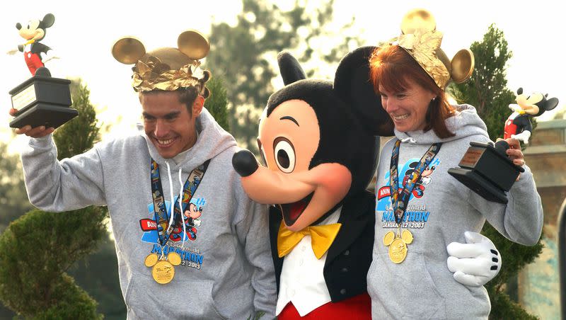 Adriano Bastos, left, of Sao Paulo, Brazil, and Bea Marie Altieri, of Clermont, Fla., pose with Mickey Mouse after receiving their trophies for winning their respective divisions in the Walt Disney World Marathon in Lake Buena Vista, Fla., Sunday morning, Jan. 12, 2003. More than 22,000 racers took part in the 10th anniversary of the event.