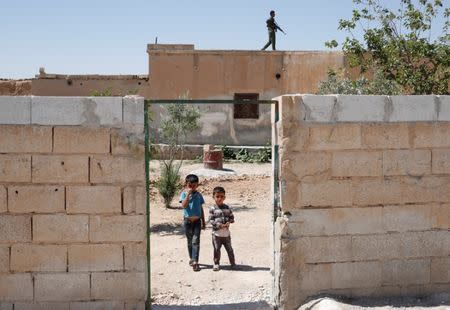 Children look at Islamic State prisoners who were pardoned by a council that is expected to govern Raqqa once the group is dislodged from the Syrian city in Ain Issa village, north of Raqqa, Syria June 24, 2017. REUTERS/Goran Tomasevic