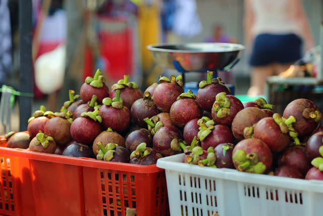 <p>Elizabeth Beard / Getty Images</p> Baskets of purple mangosteens for sale at a small market at a temple in Bali, Indonesia.