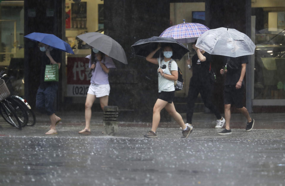 People walk in the rain caused by Typhoon Chanthu in Taipei, Taiwan, Sunday, Sept. 12, 2021. Typhoon Chanthu drenched Taiwan with heavy rain Sunday as the storm’s center passed the island’s east coast heading for Shanghai. (AP Photo/Chiang Ying-ying)