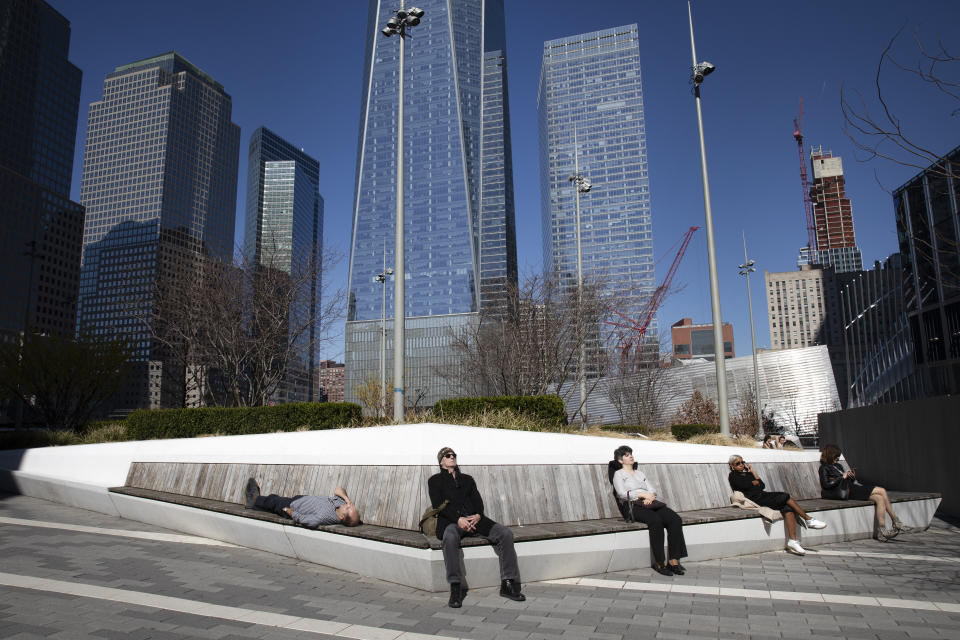 FILE - In this March 9, 2020, file photo, people rest in the sunshine in the World Trade Center's Liberty Park. As outbreaks of the new virus that first emerged in China continue to spread in countries, particularly those experiencing winter, one of the biggest unanswered questions is how COVID-19 will behave in warmer weather. (AP Photo/Mark Lennihan, File)