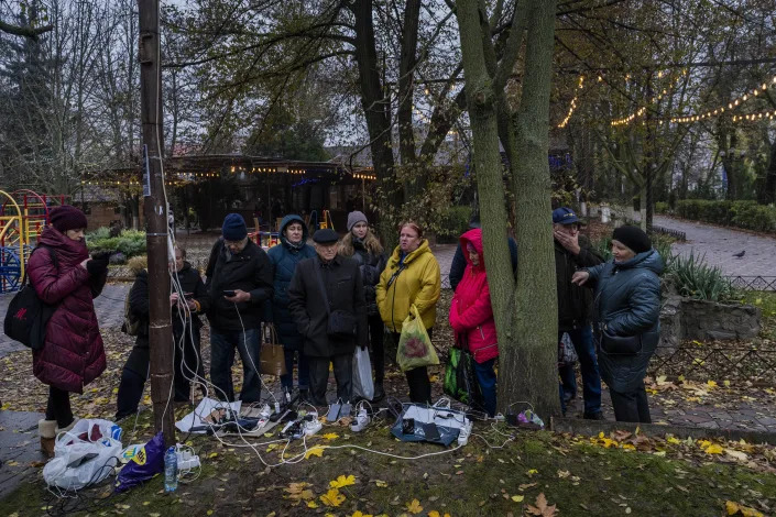 FILE - Residents plug in mobile phones and power banks at a charging point in downtown Kherson, southern Ukraine, Sunday, Nov. 20, 2022. The Russian withdrawal from the only provincial capital it gained in nine months of war was one of Moscow most significant battlefield losses. Now that its troops hold a new front line, the Ukrainian military said through a spokesman, the army is planning its next move. (AP Photo/Bernat Armangue, File)