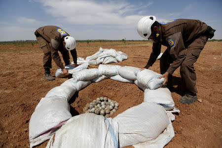 Civil defence members gather cluster bomblets to safely detonate them in a field in al-Tmanah town in southern Idlib countryside, Syria May 21, 2016. REUTERS/Khalil Ashawi/File Photo
