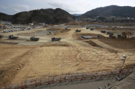 In this March 5, 2016, file photo, Trucks line up in queue to dump soils in the tsunami and earthquake destroyed town of Onagawa, Miyagi Prefecture, northern Japan. (AP Photo/Eugene Hoshiko, File)