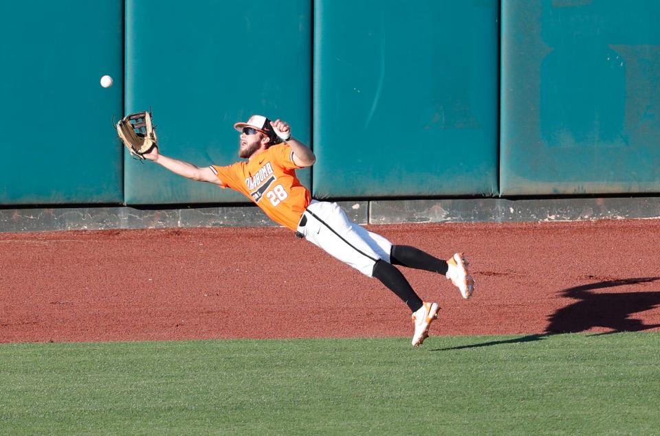 Oklahoma State outfielder Caeden Trenkle (28) leaps and makes a catch on a West Virginia fly ball Friday in the Cowboys' 12-2 win in the Big 12 baseball tournament at Chickasaw Bricktown Ballpark.