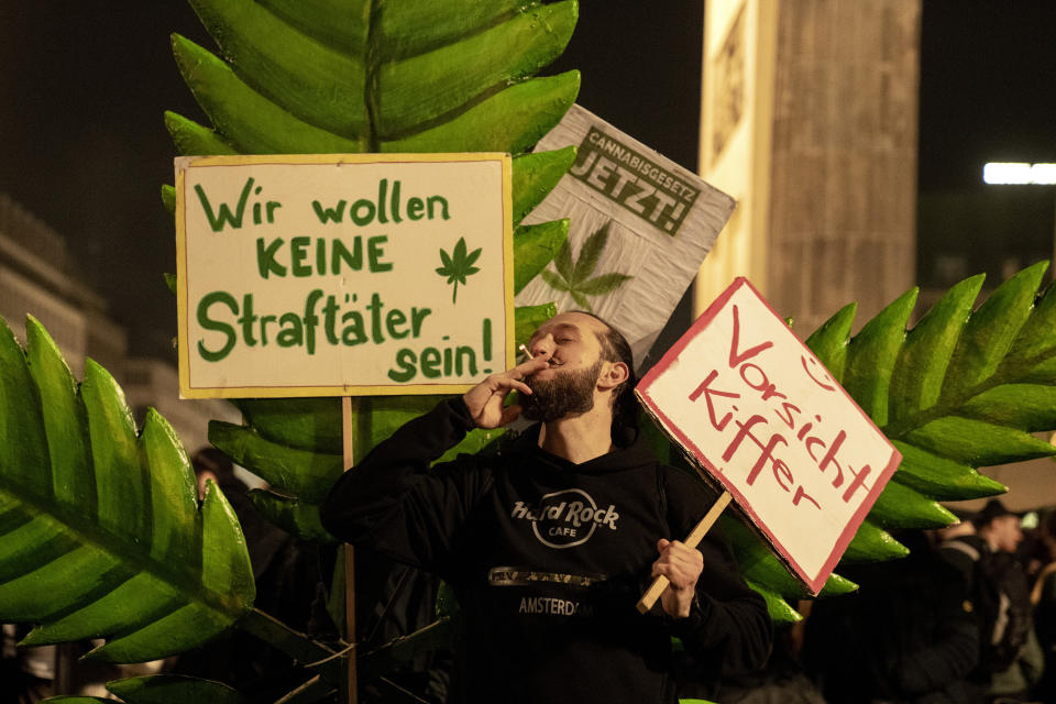 A man takes a puff from a marijuana cigarette next to a placard reading "We don't want to be offenders!" in front of the Brandenburg Gate during the "Smoke-In" event in Berlin, Germany, Monday, April 1, 2024. Starting 1 April, Germany has legalised cannabis for personal use. As per the new law, Adults aged 18 and over will be allowed to carry up to 25 grams of cannabis for their own consumption. (AP Photo/Ebrahim Noroozi)