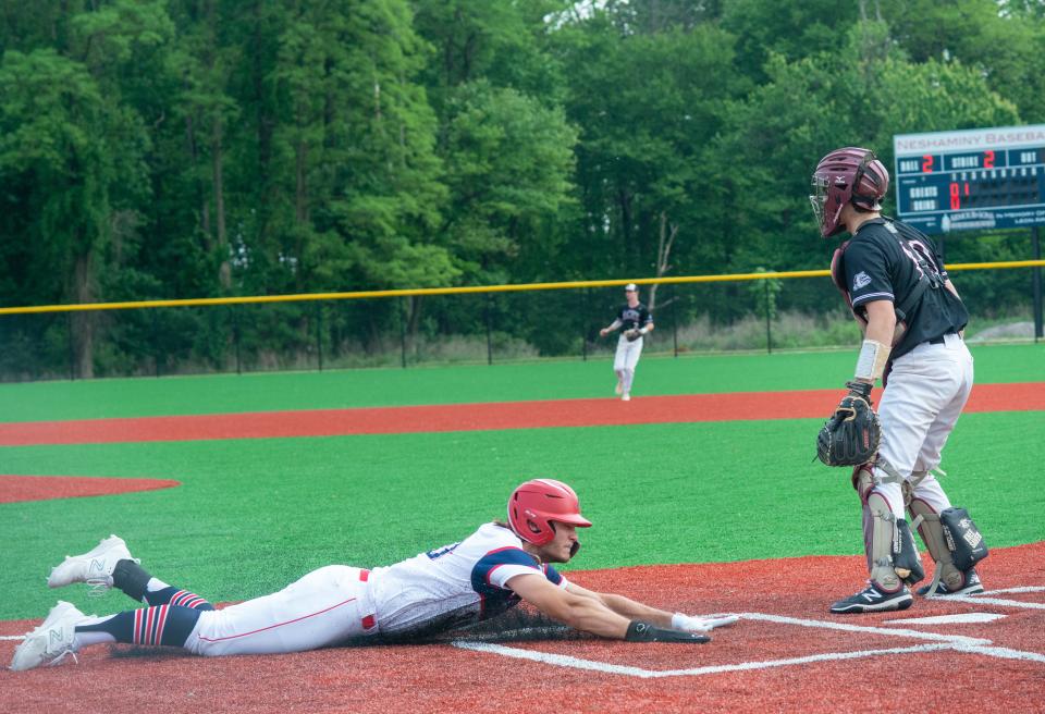 Neshaminy’s Stone Powell slides safely at home as Lower Merion catcher Max Rogers awaits a throw in the second inning of Monday's PIAA District One first-round playoff game.