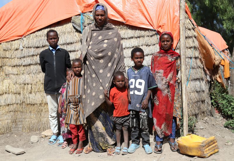 Internally displaced Ethiopian woman stands surrounded by six of her seven children outside her hut in Tuli Guled