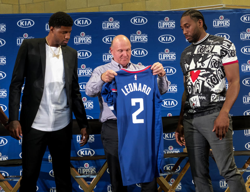 Los Angeles Clippers team chairman Steve Ballmer, center, presents a new team jersey to Kawhi Leonard, right, as Paul George looks on during a press conference in Los Angeles, Wednesday, July 24, 2019. Nearly three weeks after the native Southern California superstars shook up the NBA by teaming up with the Los Angeles Clippers, the dynamic duo makes its first public appearance. (AP Photo/Ringo H.W. Chiu)