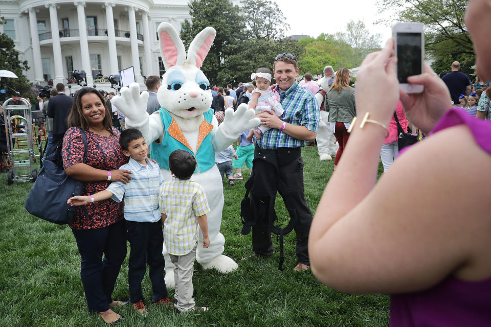 Families pose for photographs with one of the costumed Easter Bunny characters.&nbsp;